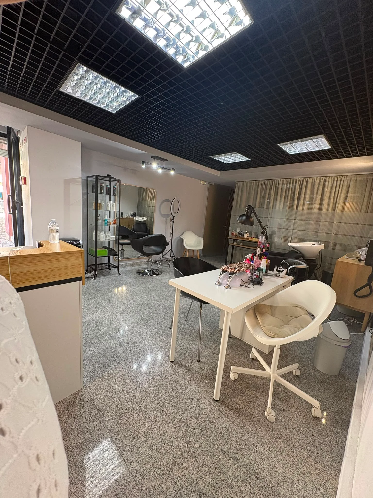 Vista real do salão, com cadeira de cabeleireiro e zona de manicure